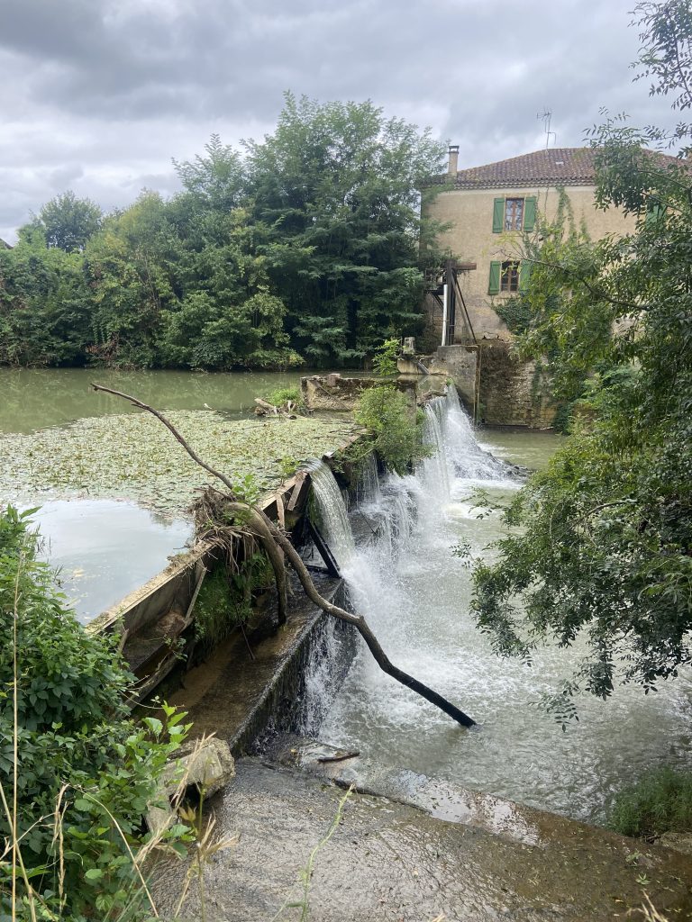 Image of an old house in a grey weather with a stream of water cascading in front evoking sadness and longing